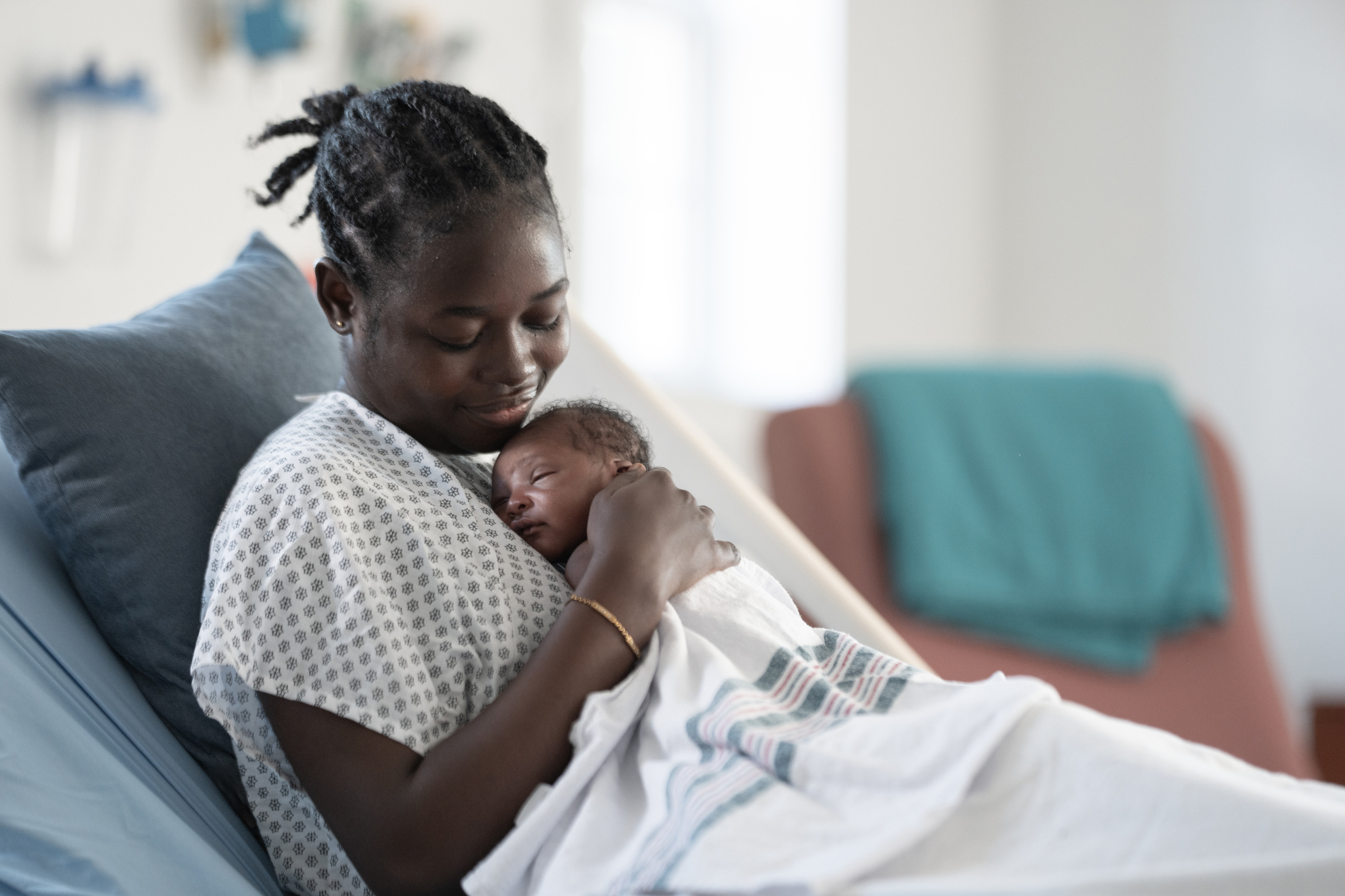 Black Mother Cradling Newborn Baby in Hospital Bed During Postpartum Moment